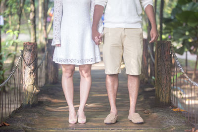 Low section of friends standing on tree trunk