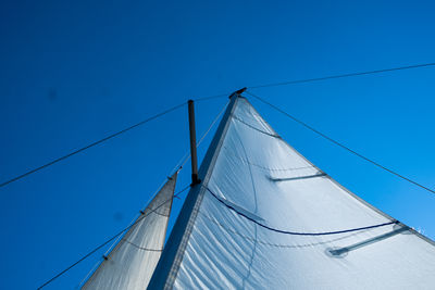 Low angle view of sailboat against clear blue sky