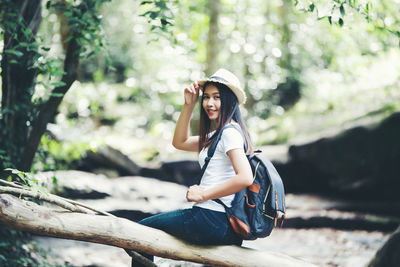 Portrait of young woman sitting on tree