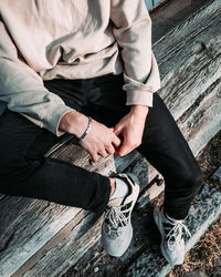 Low section of man sitting on wood