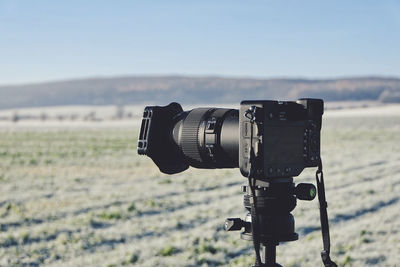 Close-up of camera on landscape against sky