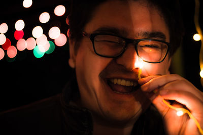 Close-up of happy young man holding illuminated light