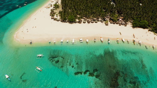 Seascape with beautiful beach and tropical island palm trees by coral reef from above. daco island