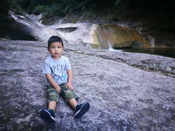 Portrait of boy on rock at shore