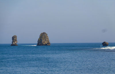 Scenic view of rocks in sea against clear sky