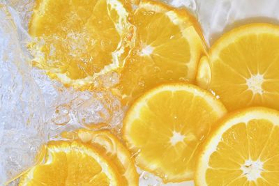 Slices of oranges in water on white background. oranges close-up in liquid with bubbles. slices