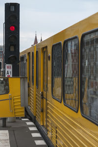 Yellow train against sky in city