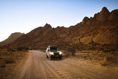 Cars on road in desert against clear sky