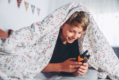 Close-up of boy holding walkie-talkie at bed 