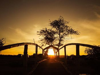 Silhouette tree by bridge against sky during sunset