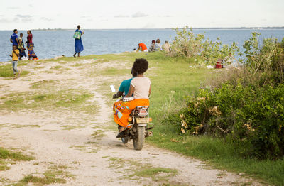 Rear view of people riding motorcycle on road