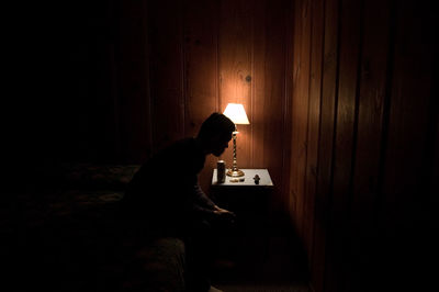 Side view of man sitting on table at home