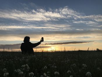 Silhouette person standing on field against sky during sunset