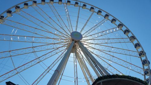 Low angle view of ferris wheel against clear blue sky