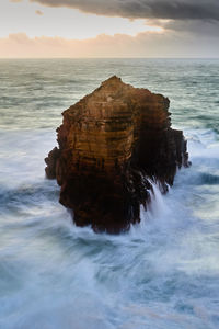 Rock formation in sea against sky