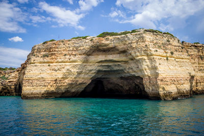 Rock formation by sea against sky