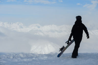 Silhouette man on snowcapped mountain against sky