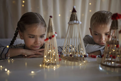 Cute sibling looking at illuminated christmas ornament