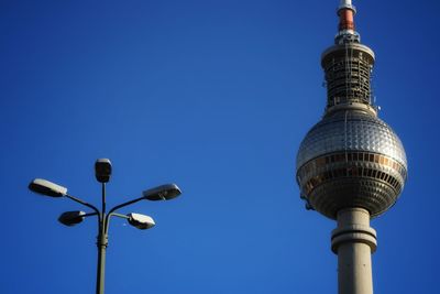 Low angle view of communications tower against blue sky