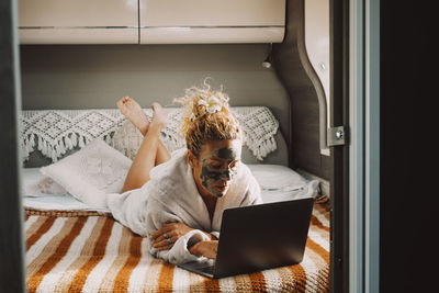 Side view of woman using laptop while sitting at home