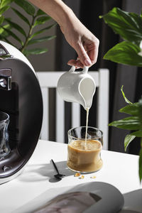 Cropped hand of person pouring drink on table