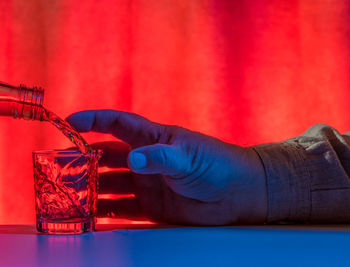 Midsection of man holding red glass on table