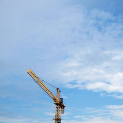 Low angle view of crane at construction site against sky