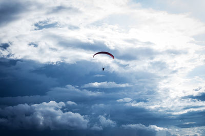 Low angle view of person paragliding against sky