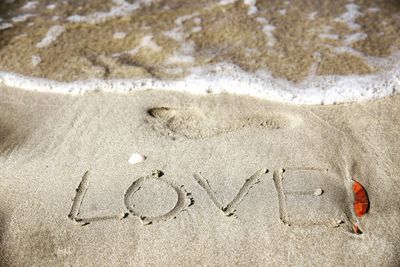High angle view of love text on sand at sea shore