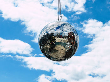 Low angle view of disco ball hanging against sky