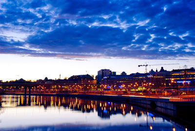 Illuminated bridge over river against sky at dusk