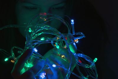 Close-up of woman with illuminated string light