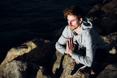 High angle view of young man sitting on rock