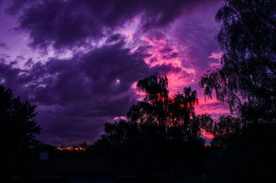 Low angle view of silhouette trees against dramatic sky