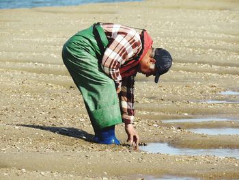 Rear view of man bending on beach