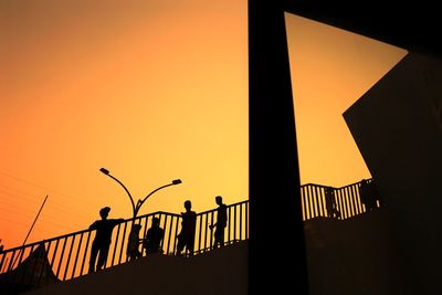 Low angle view of silhouette street lights against orange sky