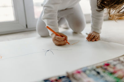 Midsection of girl drawing on paper