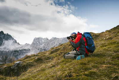 Man photographing on mountain against sky