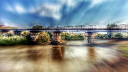 Bridge over river against sky in city