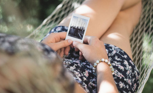 Midsection of woman holding smart phone outdoors