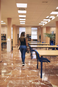 Girl with mask and backpack enters an empty library