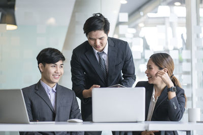 Young couple looking away while sitting in laptop