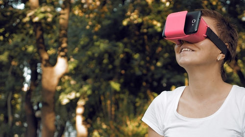 Woman using virtual reality simulator against trees