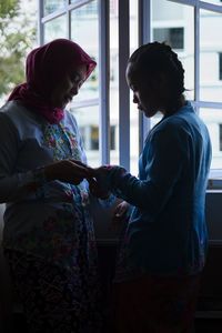 Woman wearing traditional clothing standing with daughter at home