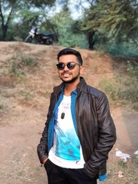 Portrait of young man wearing sunglasses standing in forest