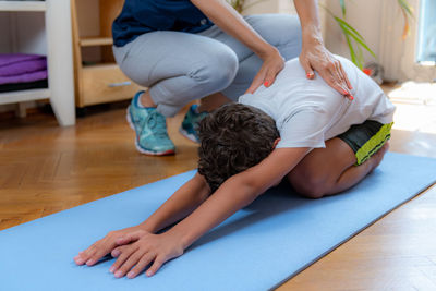 Lower back stretch. boy exercising with physical therapist.