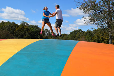 Low angle view of couple bouncing on castle against sky