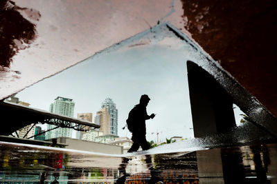 Reflection of man on puddle at street