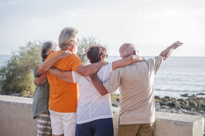 People standing by sea against sky