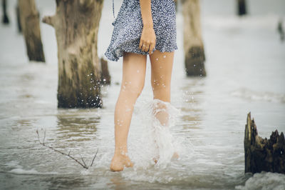 Low section of woman standing in water